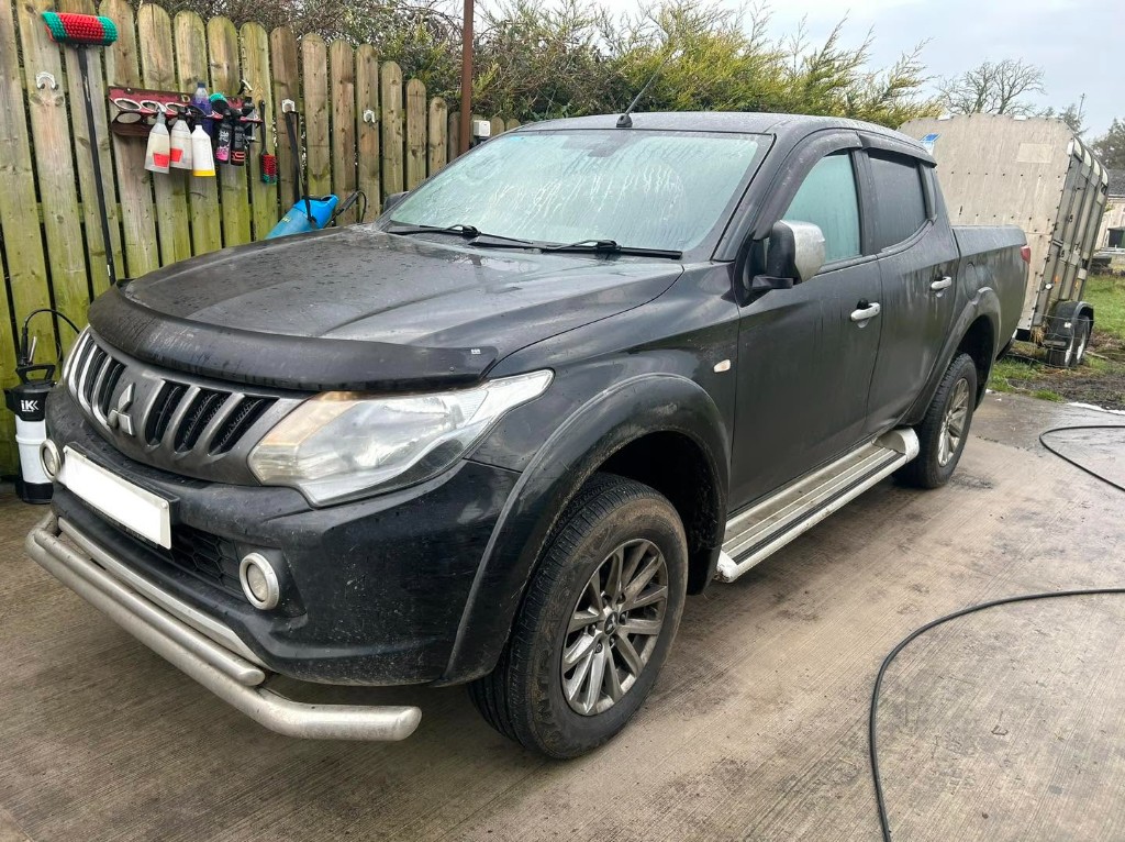 Muddy black Mitsubishi L200 pickup before cleaning